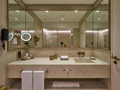 Moderner Badezimmerwaschtisch mit großem Spiegel, goldfarbenen Armaturen und weißen Handtüchern.