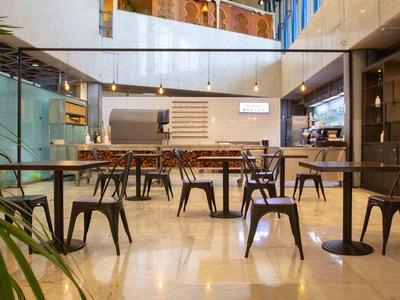 Moderner, offener Innenraum mit Tischen, Stühlen, Glaswänden und Holzdecke in warmem Licht.