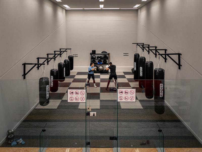 Innenraum eines Helmkampfsport-Trainingsraums mit Boxsäcken und Trainingsgeräten, gut beleuchtet.