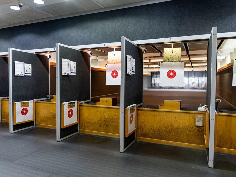 Schießstand mit mehreren Boxen, Holztrennwänden und roten Zielscheiben an der Rückwand.