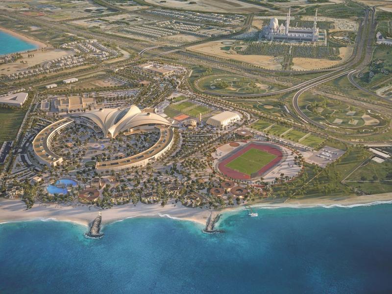 Luftaufnahme eines Küstenresorts mit Wasserpark, Stadion und grünem Park nahe dem Meer.