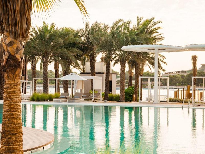 Großes Industriegebäude mit Parkplätzen, Straße im Vordergrund, städtische Umgebung und blauer Himmel.