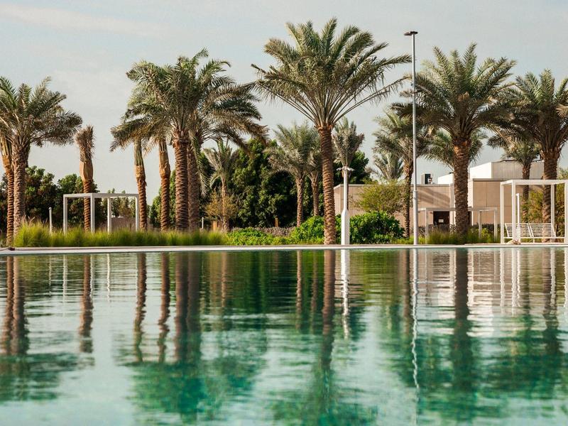 Ein ruhiger Pool mit klarer Wasserfläche, umgeben von hohen Palmen und grüner Vegetation.