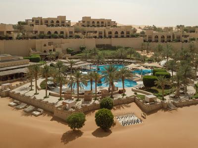 Hotel di lusso con piscina e lettini in un paesaggio desertico al tramonto