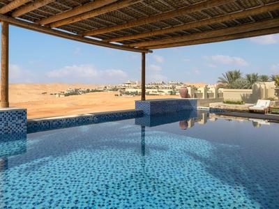Piscina con acqua blu sotto un'area coperta con vista sul paesaggio desertico.