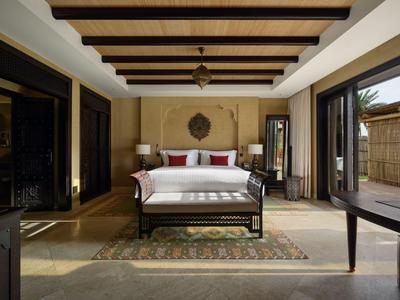 Spacious hotel room with sofa, wooden beams, rug, and sliding glass doors leading outside.