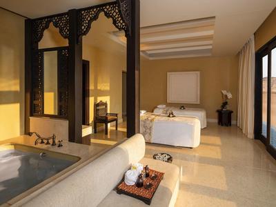 Modern hotel room with large bed, bathtub, and sliding glass doors leading outside.