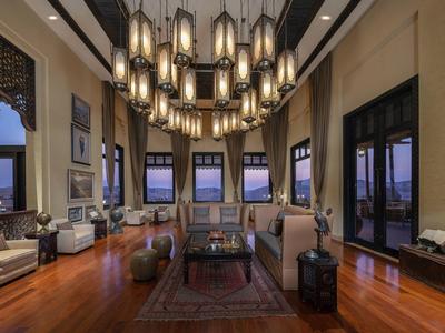 Elegant hotel lounge with wooden floors, large windows, multiple armchairs, and modern pendant lights.