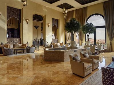 Luxurious hotel lobby with elegant seating, tall windows, and warm lighting.