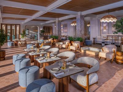 Área de salón acogedora en hotel con grupos de asientos, mesas e iluminación cálida.