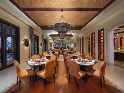 Ristorante elegante con pavimento in legno, tavoli apparecchiati e sedie comode in un hotel.