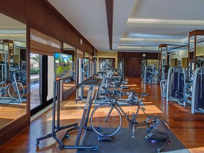 Palestra moderna con attrezzature, pavimento in legno e grandi specchi in un hotel.