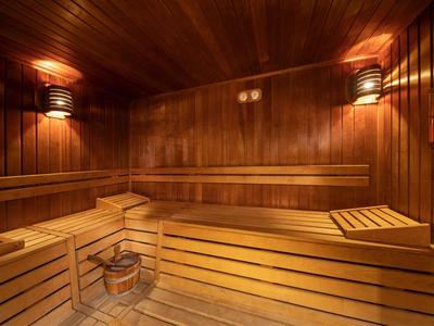 Cozy wooden sauna room with benches, a bucket, and warm lighting on the walls.