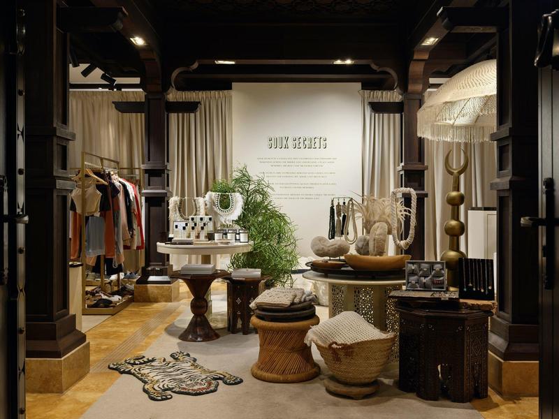 Luxury boutique interior with elegant furniture, clothing racks, and decorative plants.