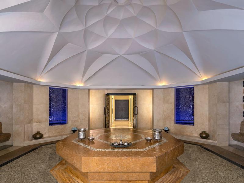 Elegant spa interior with domed ceiling, central hexagonal bath, and comfortable seating.