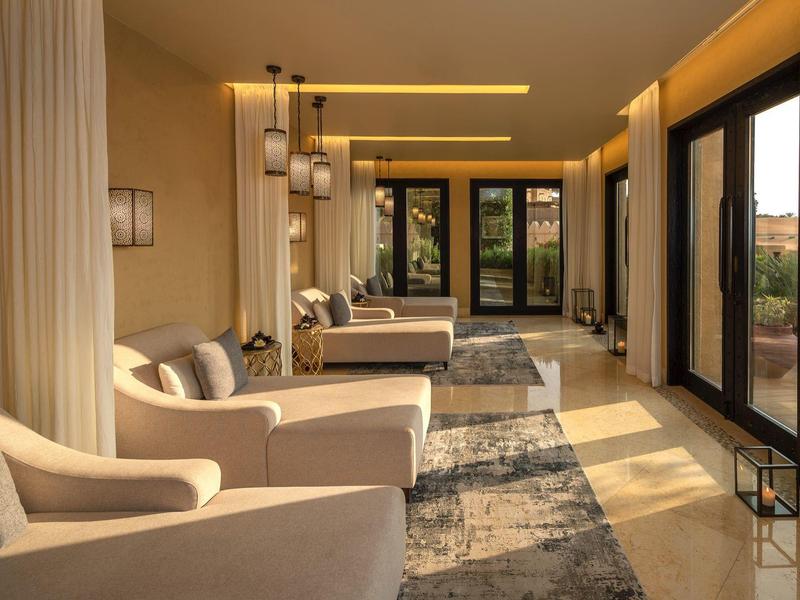 Hotel lounge with beige armchairs, large windows, and warm ambient lighting.