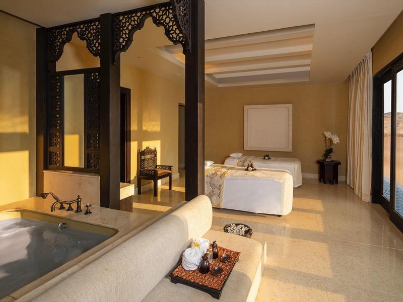 Modern hotel room with large bed, bathtub, and sliding glass doors leading outside.