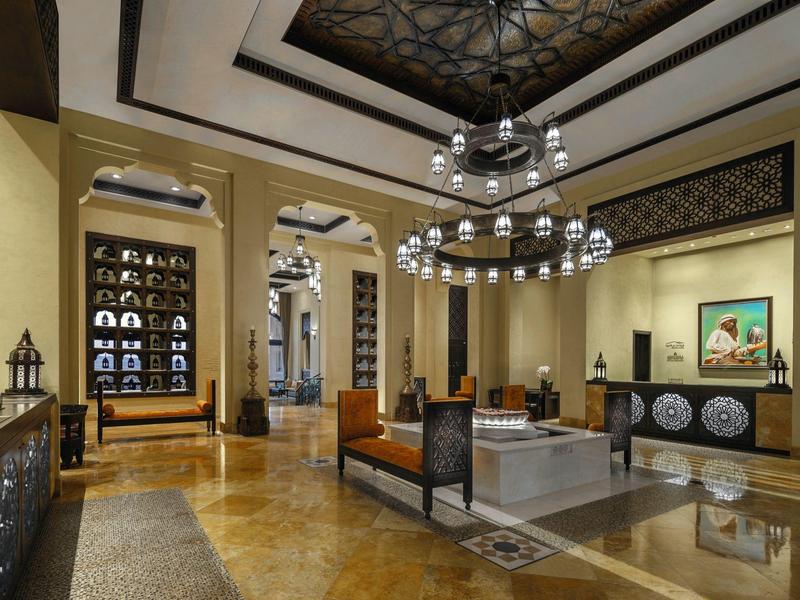 Luxurious hotel lobby with elegant chairs, chandeliers, and decorative ceiling design.