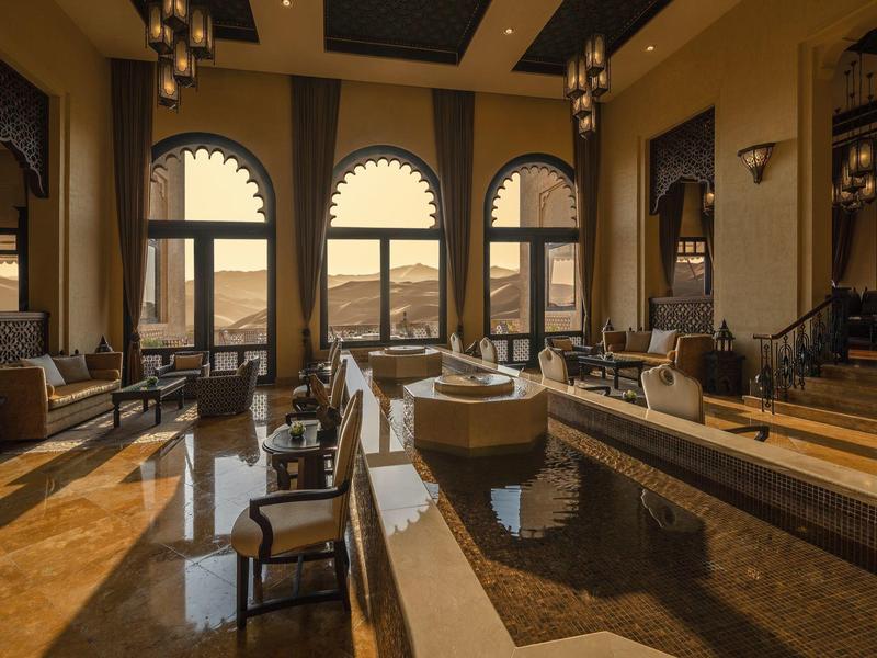 Luxury hotel lobby with large arched windows, elegant seating, and a central water feature.