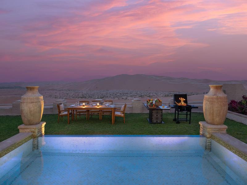 Luxury pool overlooking a cityscape during a pink and purple sunset.
