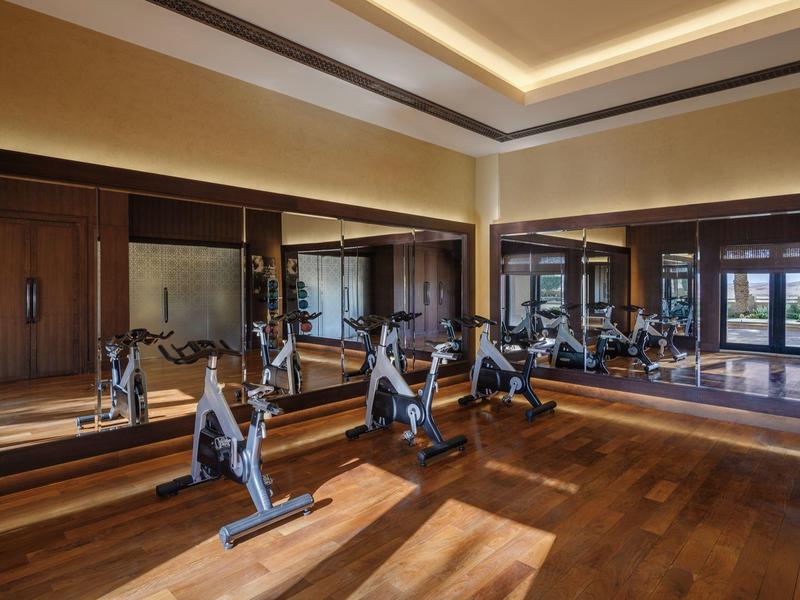 Spacious gym with wooden floors, mirrors on walls, and multiple stationary bikes.