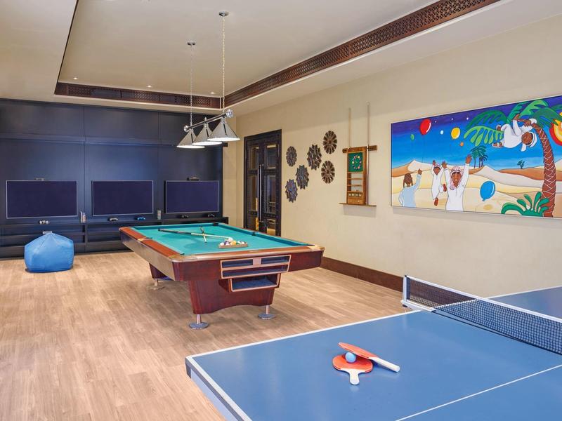 Recreation room with billiards and ping pong table, lounge seating, and tropical wall art.