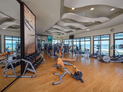 Salle de sport avec équipements modernes et grandes fenêtres donnant sur la mer.