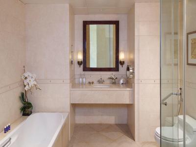 Helles Badezimmer mit Badewanne, Glasdusche, Spiegel, Waschbecken und dezenten Wandfliesen.