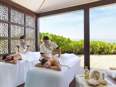 Zwei Männer erhalten in einem offenen Pavillon entspannende Rückenmassagen, umgeben von Natur.