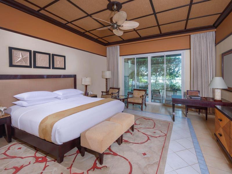 Geräumiges Schlafzimmer mit King-Size-Bett, Holzmöbeln, Deckenventilator und großem Fenster.