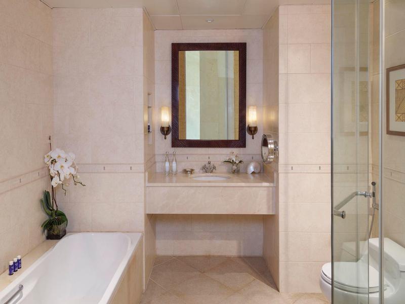 Helles Badezimmer mit Badewanne, Glasdusche, Spiegel, Waschbecken und dezenten Wandfliesen.