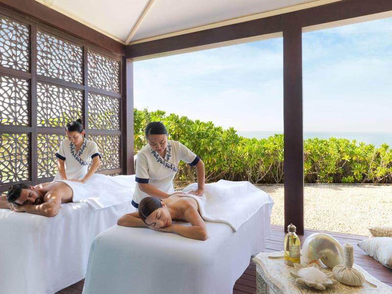 Zwei Männer erhalten in einem offenen Pavillon entspannende Rückenmassagen, umgeben von Natur.