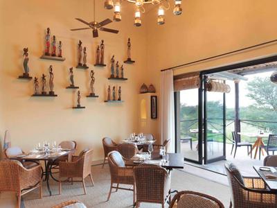 Hell eingerichtetes Restaurant mit hohen Decken und offenem Zugang zur Terrasse und Natur.