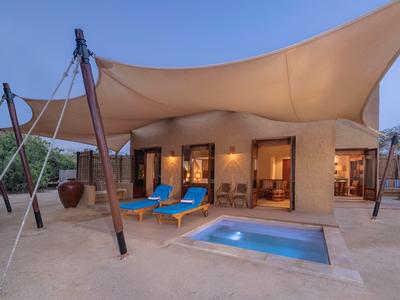 Moderner Außenbereich mit Pool und gemütlichen Liegestühlen unter Sonnensegel.