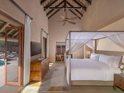 Luxe slaapkamer met hemelbed en uitzicht op een buitenzwembad.