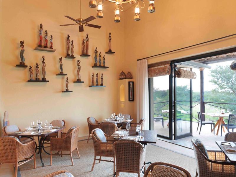 Hell eingerichtetes Restaurant mit hohen Decken und offenem Zugang zur Terrasse und Natur.