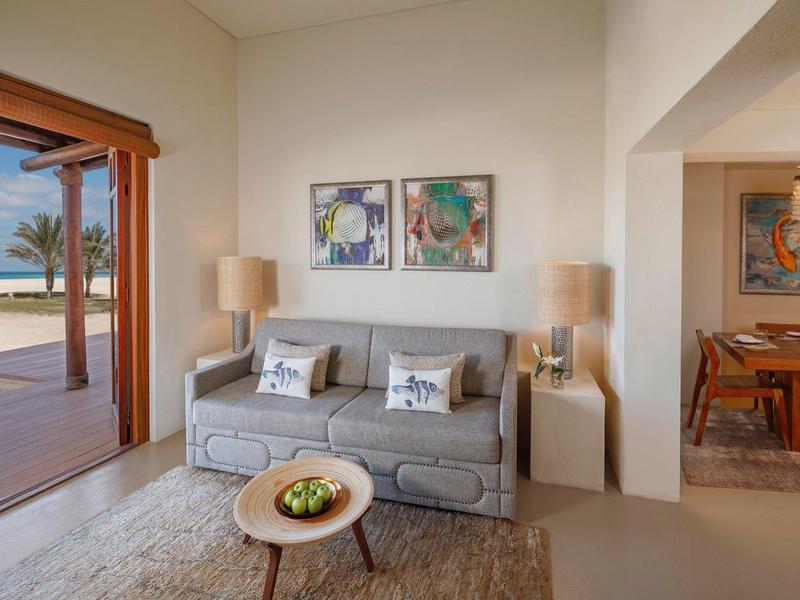Cozy living room with gray sofa and ocean view through open wooden sliding doors.