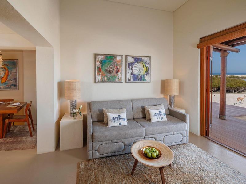 Cozy hotel room with sofa, floor lamps, art, and balcony with pool view.