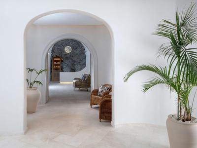 Hell gestalteter Innenbereich mit weißen Wänden, großen Pflanzen und architektonischen Bögen.