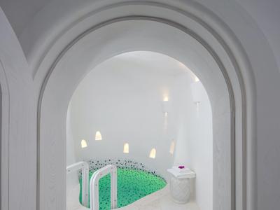 White arched spa room with built-in jacuzzi and soft lighting.