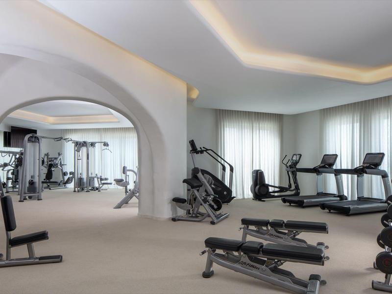 Modern gym with various exercise equipment and a large mirror.