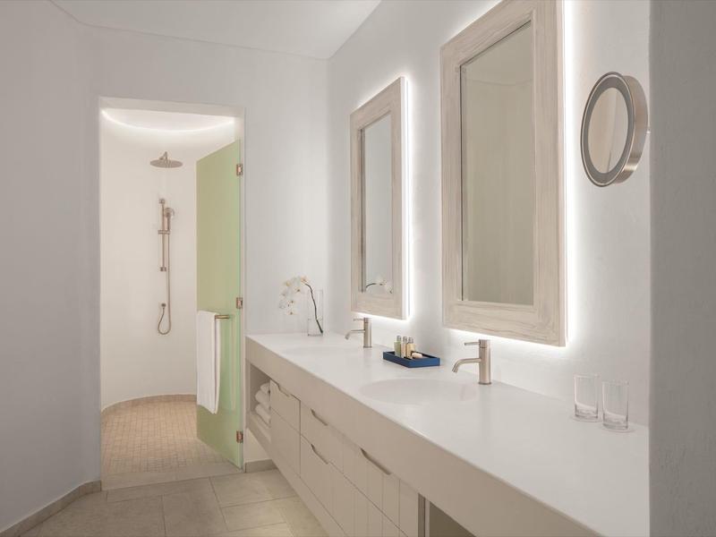 Modern bathroom with two illuminated mirrors and entrance to shower