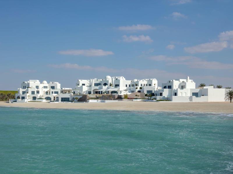White buildings on the beach with blue sky and turquoise sea.