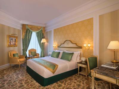 Luxuriöses Hotelzimmer mit großem Bett, grünen Akzenten und elegantem Teppichboden.
