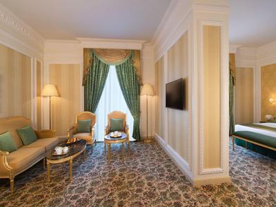 Eleganter Hotelbereich mit Sofa, Sesseln, Teppich und Blick ins Schlafzimmer.
