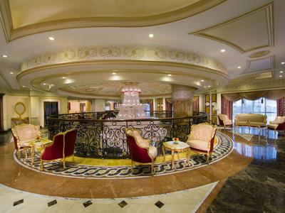 Elegante Hotellobby mit luxuriösen Sesseln und zentralem Springbrunnen unter gewölbter Decke.