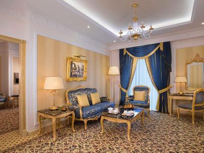 Elegantes Hotelzimmer mit blau-goldenem Interieur, Teppichboden und edlen Möbeln.