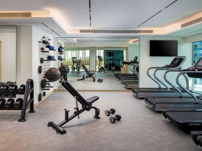 Moderner Hotel-Fitnessraum mit Hanteln, Laufbändern und Spiegeln.