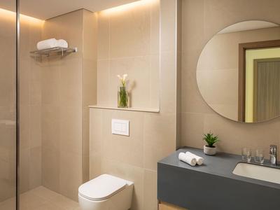 Modernes Badezimmer mit runden Spiegel, Toilette und grauem Waschtisch.
