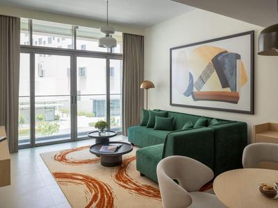 Modernes Hotelzimmer mit grünem Sofa, großem Fenster und abstrakter Kunst im Hintergrund.